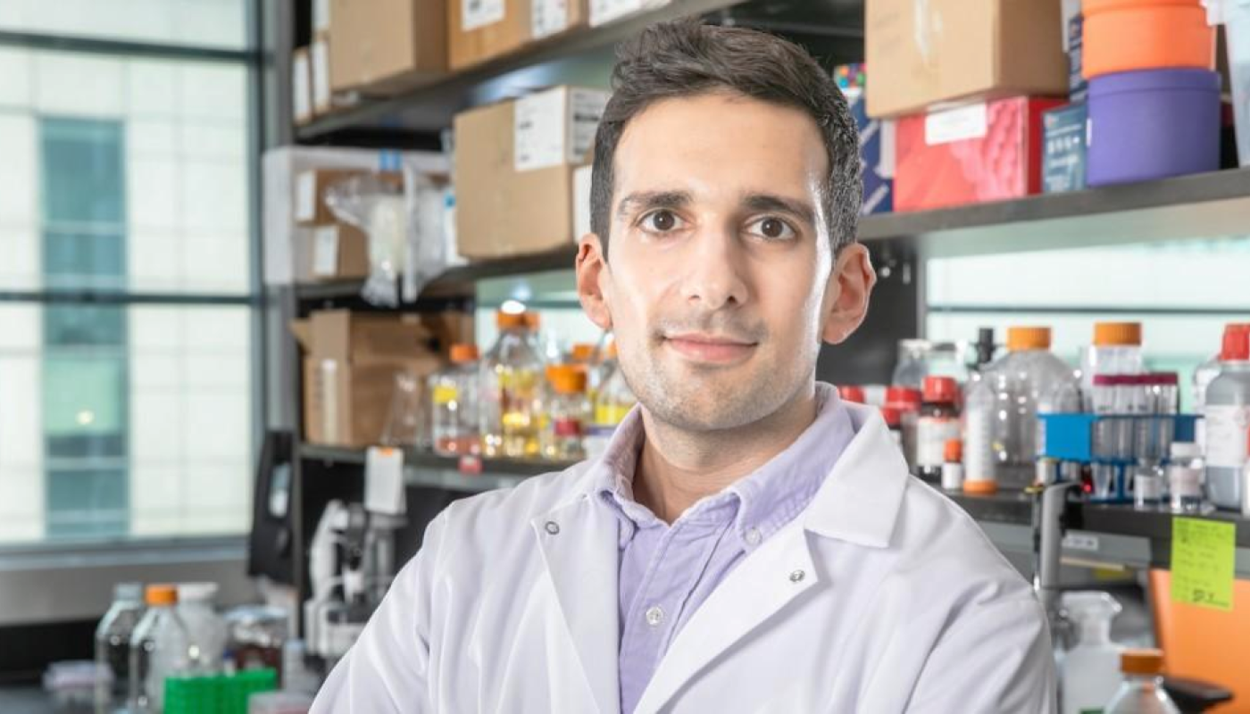Image of Columbia Professor Santiago Correa standing in a laboratory in front of shelves with lab supplies.