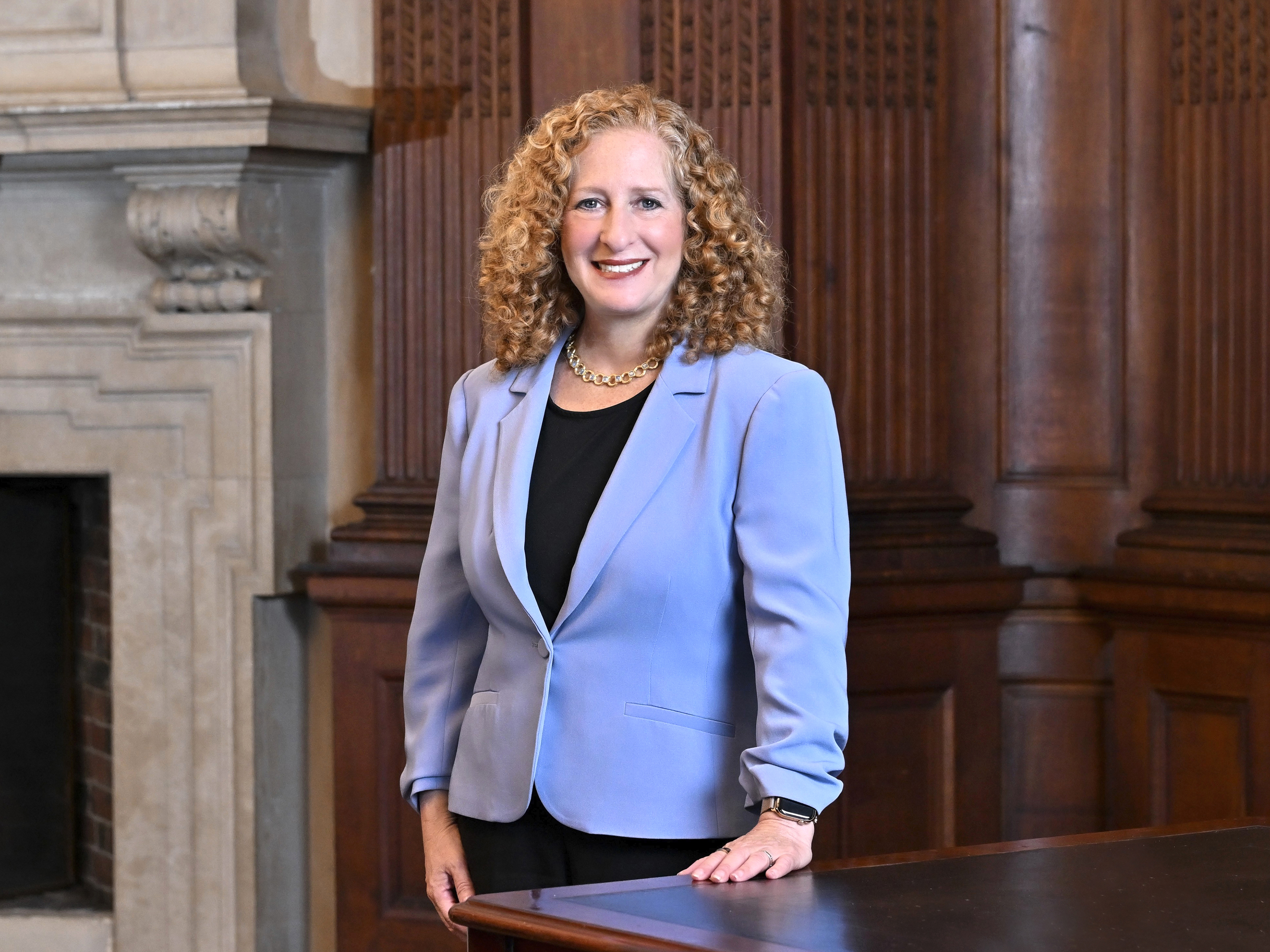 Image of President Jennifer L. Mnookin in a Columbia-blue blazer with her hand on a conference table. 