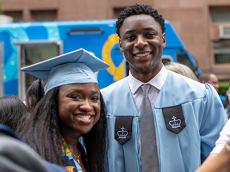 Two students wearing Columbia commencement gowns at graduation