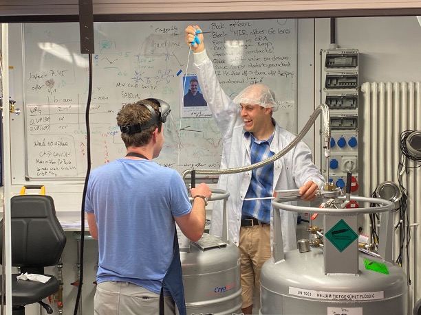Two people with lab equipment, one with his hand raised in triumph