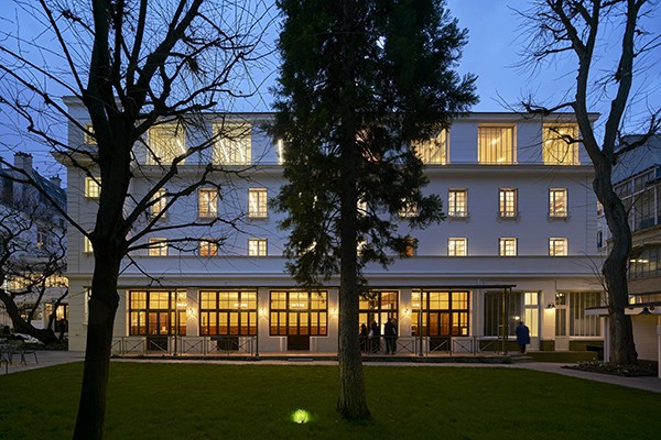 A building at Reid Hall in Paris, at twilight. in front of a green lawn.