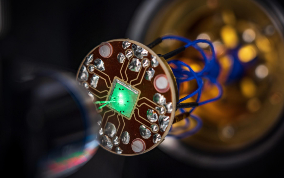 On-chip device where laser light is focused through a microscope to probe and control the material’s electronic behavior