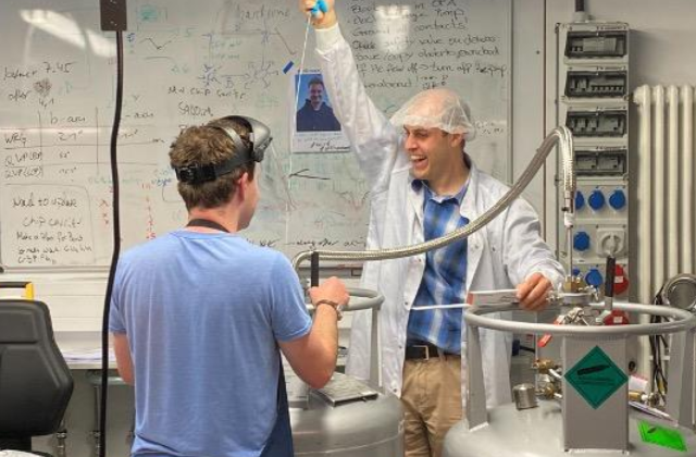 Two people with lab equipment, one with his hand raised in triumph