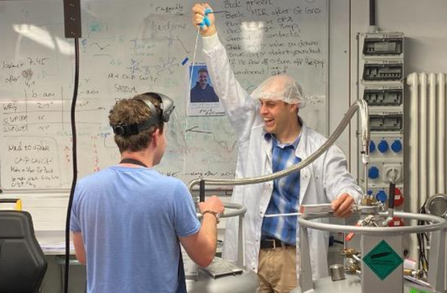 Two people with lab equipment, one with his hand raised in triumph