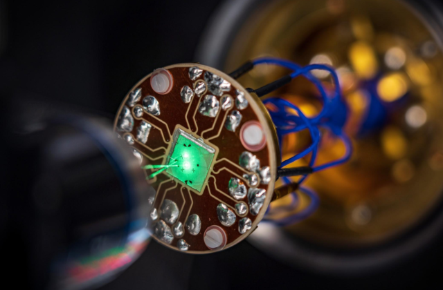 On-chip device where laser light is focused through a microscope to probe and control the material’s electronic behavior
